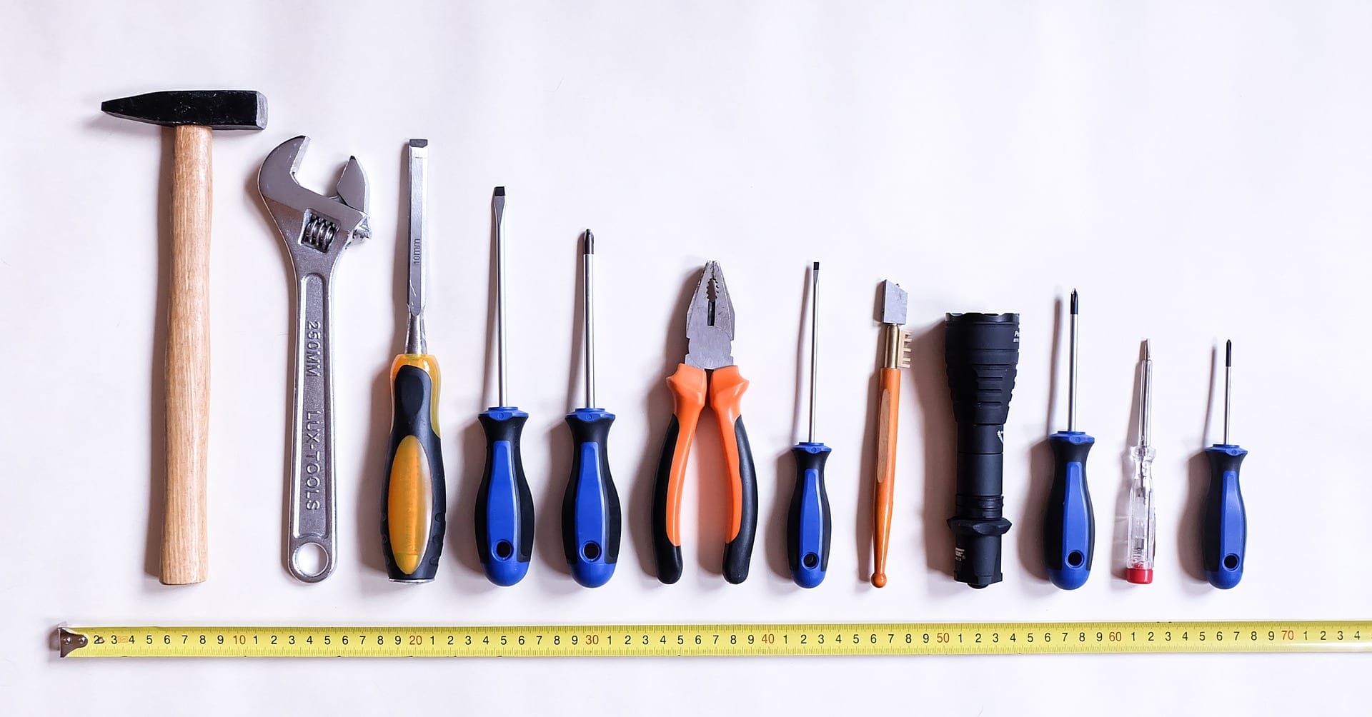 tools lined up on white background with a tape measurer underneath
