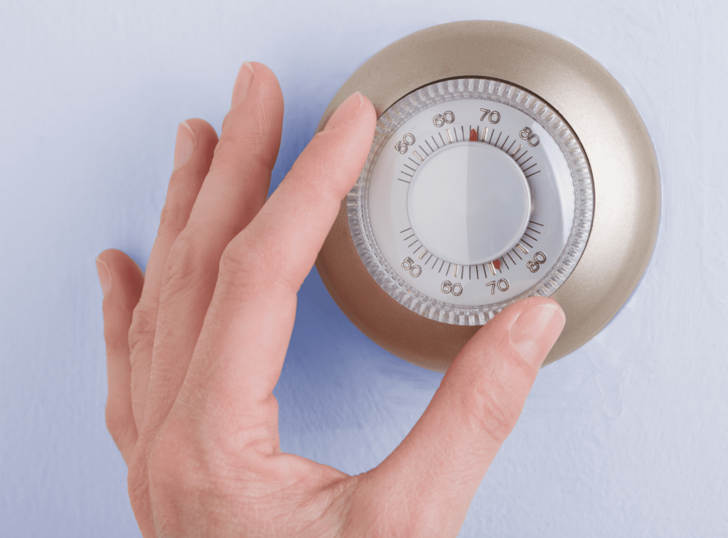 hand adjusting the thermostat