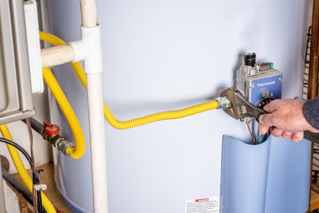 man adjusting the gas line for a residential gas-powered furnace