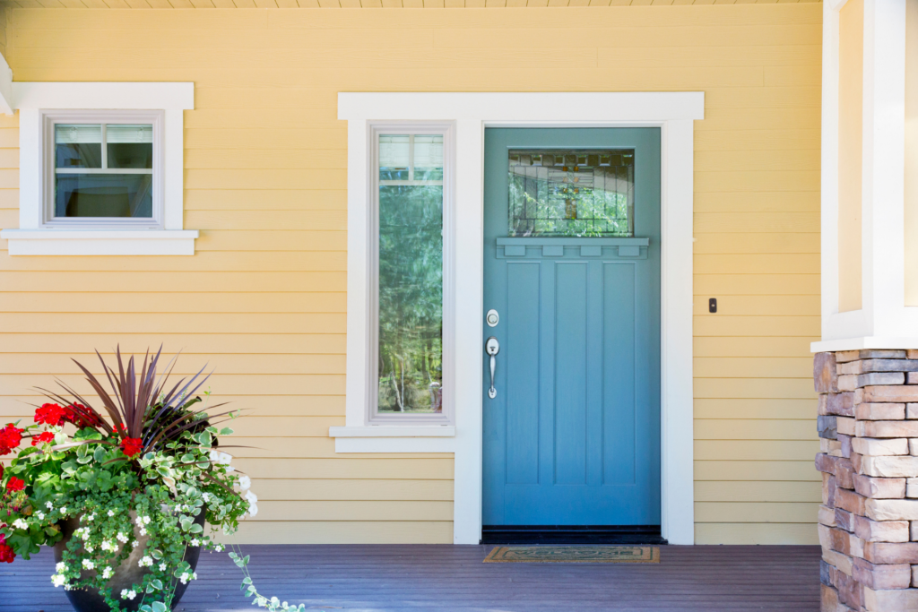 front porch of a yellow house with a blue door