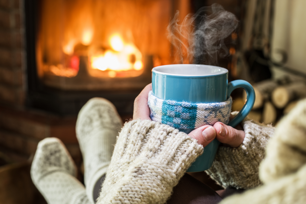 woman with cup in front of warm fireplace