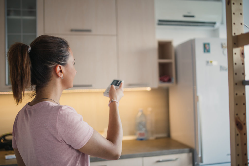 woman turning on ac system in kitchen