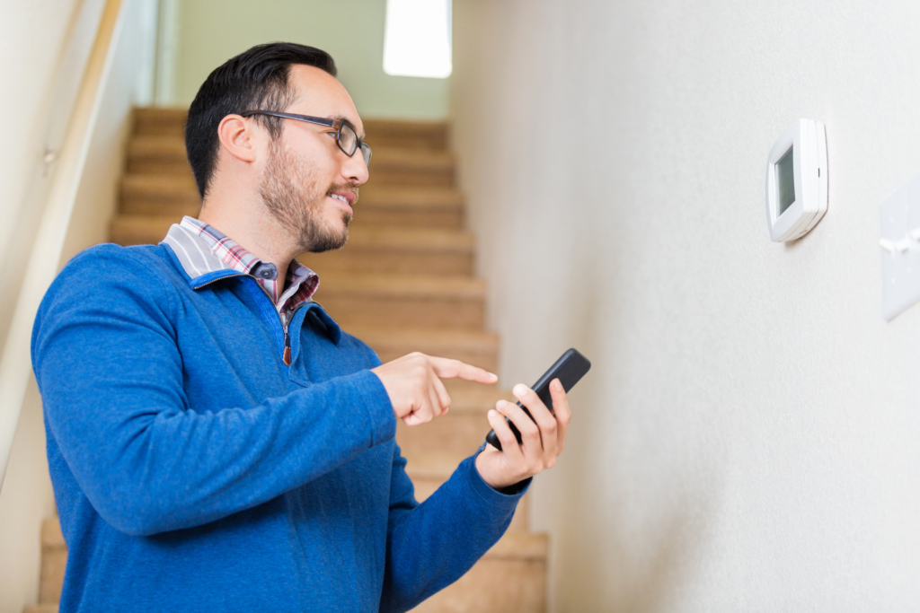 man updating thermostat settings for his home smart thermostat